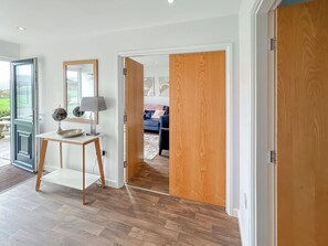 A room with a wooden floor, a white door, a mirror, a lamp, and a table with a globe. - Magnolia Lodge - UK51603 (Sunset Lakes)