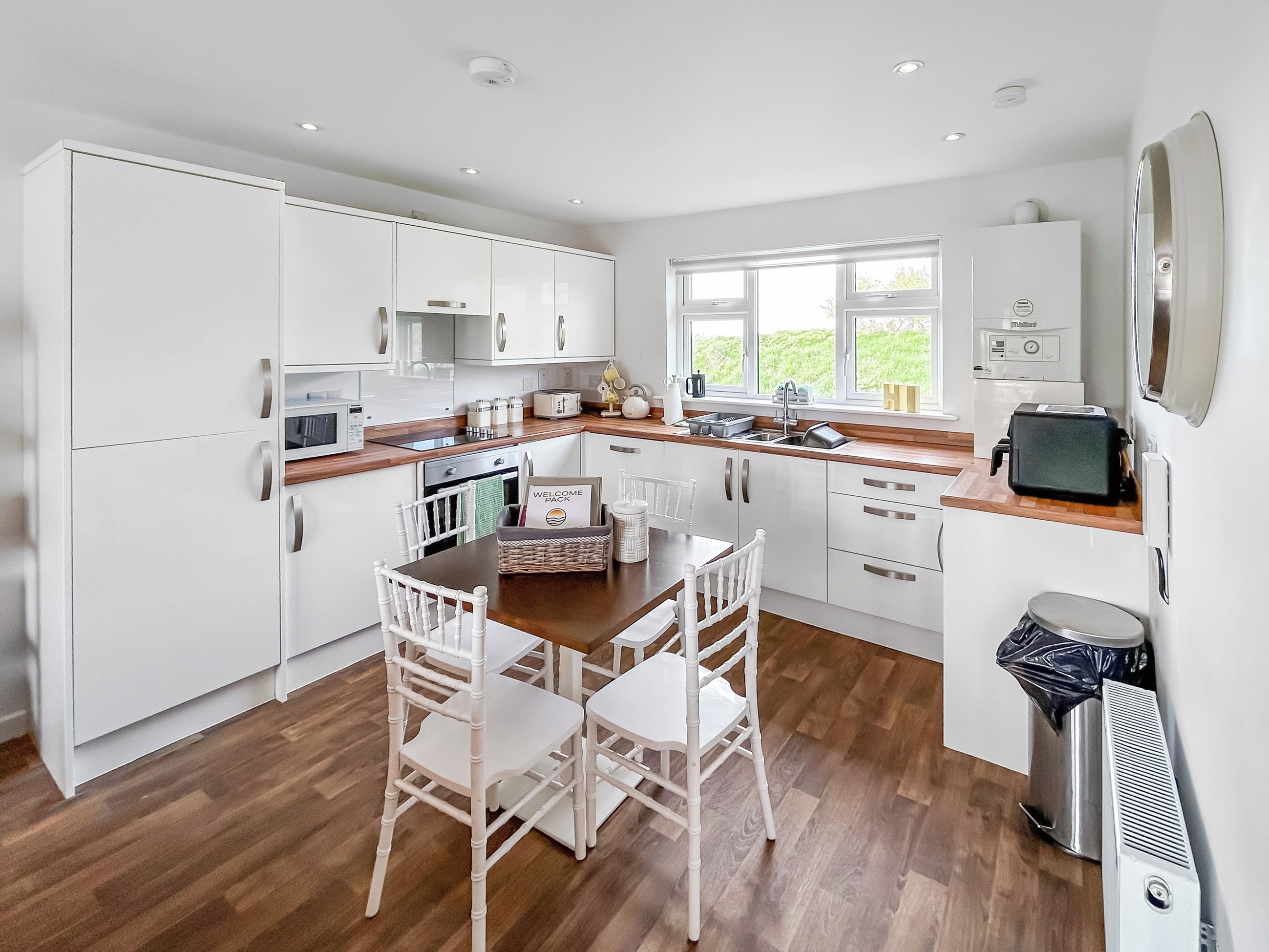 Una cocina moderna con armarios blancos, una mesa de comedor de madera y sillas.