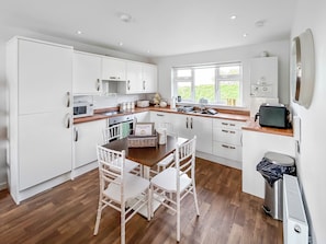 A modern kitchen with white cabinetry, a wooden dining table, and chairs.