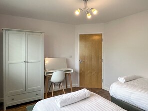 Une chambre à coucher avec un lit, un bureau et une chaise, une armoire et une porte.