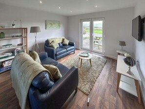 A living room with a sofa, a coffee table, a bookshelf, and a painting on the wall. - Fern Lodge - UK51604 (Sunset Lakes)