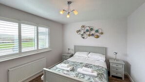 Une chambre à coucher comprenant un lit, deux tables de chevet, un luminaire fixé au mur et un radiateur.