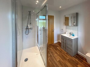 A modern bathroom with a glass-enclosed shower, a vanity with a sink, and a wooden floor. - Fern Lodge - UK51604 (Sunset Lakes)