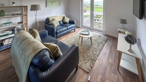 Un salon avec un canapé, une table basse, une bibliothèque et un tableau accroché au mur.