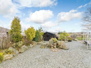 A gravel courtyard with a wooden cabin, large rocks, and various trees. - 2 bedroom accommodation in Launceston (Launceston)