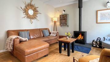 A living room with a sofa, a small table with a vase, a fireplace, and a sun-shaped wall decoration.