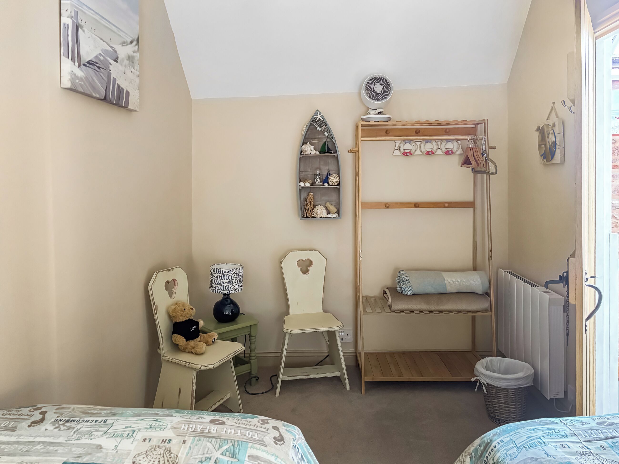 A room with bunk beds, a desk with a chair, a teddy bear, a lamp, and a radiator.