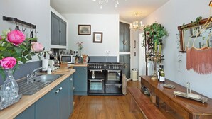 Una cocina con una isla central, estufa, lavaplatos y una araña.