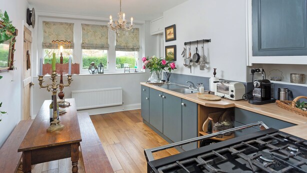 Una cocina con estufa a gas, mesa de madera y candelabro.