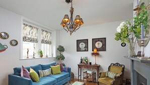 Una sala de estar con un sofá azul, una mesa de centro de madera, una chimenea y un candelabro.