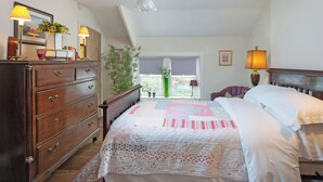 Un dormitorio con cama, cómoda, lámpara y vistas al exterior.