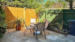 A patio with stone flooring, a wooden fence, and potted plants.