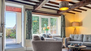 Un salon comprenant un canapé, un fauteuil et une petite table ronde avec une lampe.