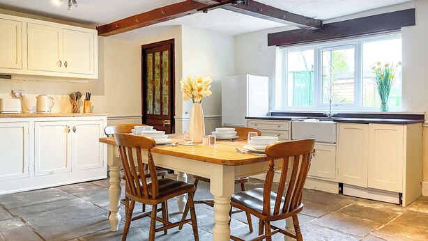 A kitchen with white cabinets, a wooden dining table, and two chairs.