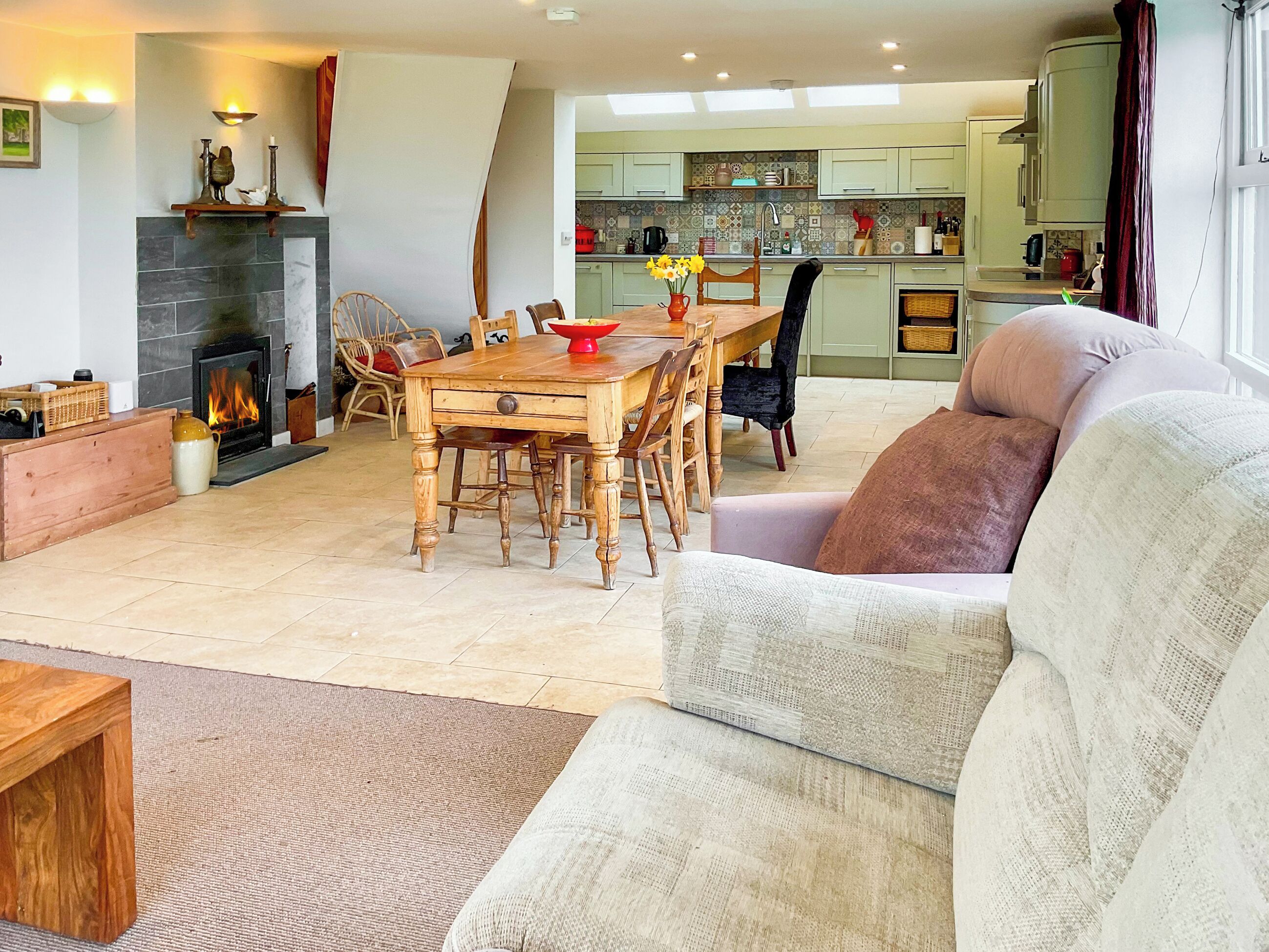 Una sala de estar con chimenea, mesa de comedor y un sofá.
