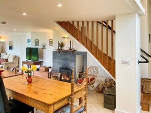 A cozy living room with a wooden dining table, chairs, a fireplace, and a staircase. - 1 bedroom accommodation in Ashmore, near Shaftesbury, (Ashmore, near Shaftesbury,)
