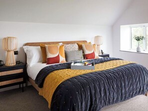 Een slaapkamer met een bed, nachtkastjes, een raam en een bedlampje.