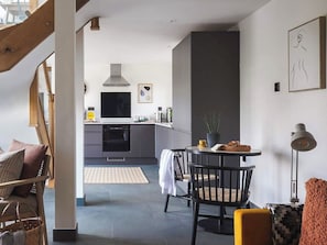 A modern kitchen with a stove, oven, and microwave. There is a dining area with a table and chairs. - 1 bedroom accommodation in Black Dog (Black Dog)