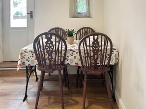Comedor con una mesa dispuesta para cuatro personas, con manteles florales y sillas de madera con diseños elaborados en el respaldo.