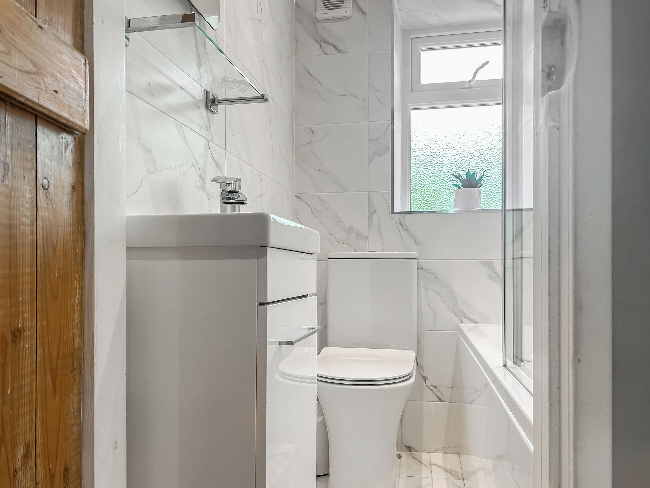 Een badkamer met toilet, wastafel en raam met plant.