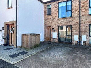 Ein Gebäude mit Ziegelaußenwand, einer Holztür mit der Nummer 14 und einer Holzbank im Innenhof.
