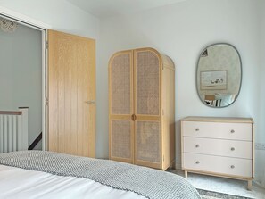 Un dormitorio con cama, armario, cómoda y espejo.