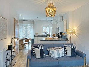 Una sala de estar moderna con un sofá, un comedor y una cocina.