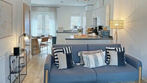 Una sala de estar moderna con un sofá, un comedor y una cocina.