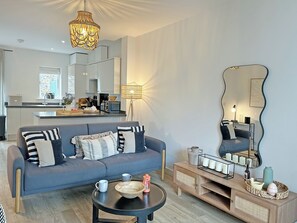 A modern living room with a sofa, coffee table, and a dining area with a kitchen in the background. - 2 bedroom accommodation in Hayle (Hayle)