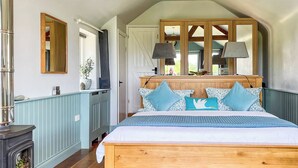 A bedroom with a bed, wooden beams, a dresser, a mirror, and a window. - 4 bedroom accommodation in St Just (St Just)
