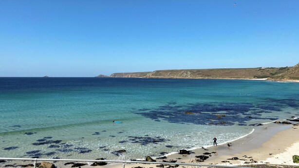 A coastal beach with clear water, rocky shoreline, and distant cliffs. - 4 bedroom accommodation in St Just (St Just)