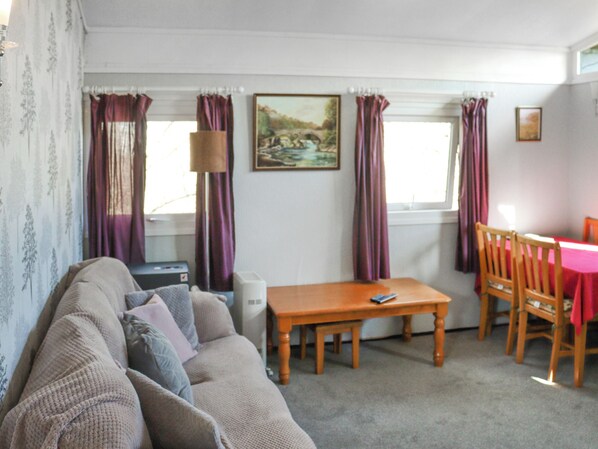 A living room with a sofa, a wooden table, and a dining area with chairs.