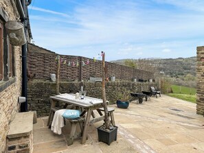 A rustic outdoor seating area with stone walls, a wooden table, and a view of the countryside. - 3 bedroom accommodation in Chisworth (Chisworth)