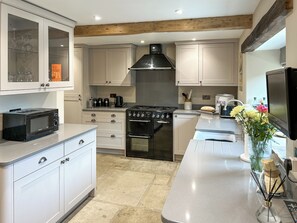 A modern kitchen with white cabinetry, a built-in stove, a microwave, and a large island with a sink. - 3 bedroom accommodation in Chisworth (Chisworth)