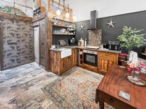 Eine Küche mit Holzausstattung, einem eingebauten Backofen und einer schwarzen Spritzschutzwand.