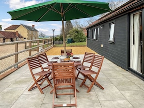 Eine Terrasse mit Tisch, Stühlen und einem grünen Sonnenschirm.
