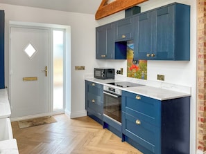 Eine Küche mit blauen Schränken, einer Mikrowelle, einem Backofen und einem Spülbecken.