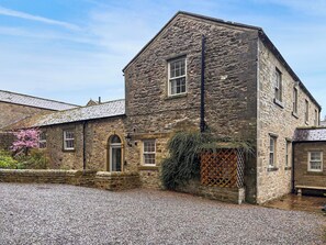 A stone building with a gravel driveway, a wooden fence, and a small garden area. - West House - UK51668 (Leyburn)