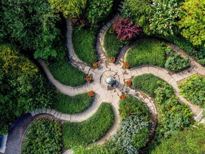 Un jardín con una estructura circular de piedra en el centro, rodeada por un camino de piedra.