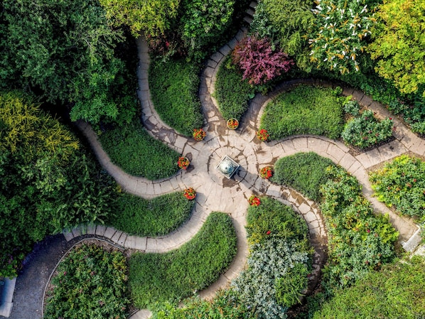 Un jardín con una estructura circular de piedra en el centro, rodeada por un camino de piedra.