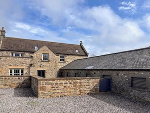 A stone building with a gravel driveway and a small entrance.