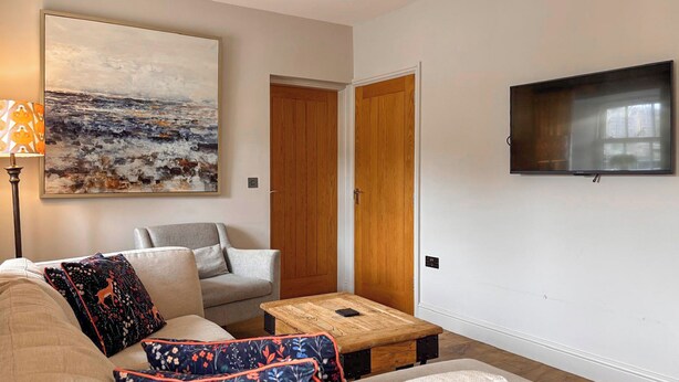 Een woonkamer met een bank, een salontafel, een televisie en een schilderij aan de muur.