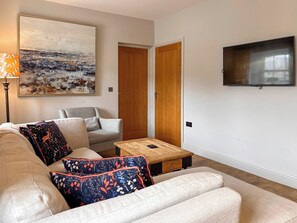 Una sala de estar con sofá, una mesa de centro, televisor y un cuadro en la pared.