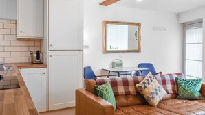 A compact living space with a kitchenette, a dining area, and a seating area with a sofa and chairs.