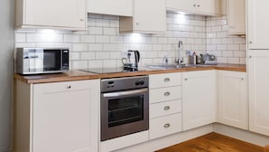 A kitchen with white cabinets, a microwave, a coffee maker, and a dishwasher.