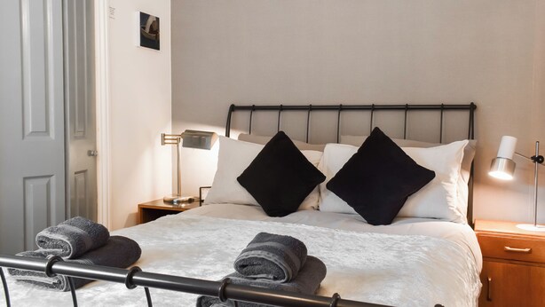 A neatly made bed with pillows, a bedside lamp, and a nightstand with a lamp.