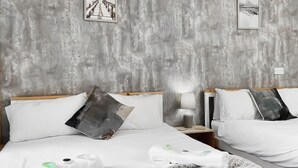 A double bed with white linens, two pillows, a bedside table with a lamp, and a wall with two framed pictures. - 5 bedroom accommodation in Pudsey, near Leeds (Pudsey, near Leeds)