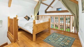 A bedroom with a wooden bed, a view through a balcony, and a patterned rug. - 5 bedroom accommodation in Shepton Mallet (Shepton Mallet)