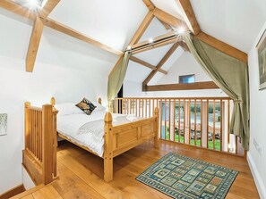 Een slaapkamer met een houten bed, uitzicht door een balkon en een kamerkleed met patroon.
