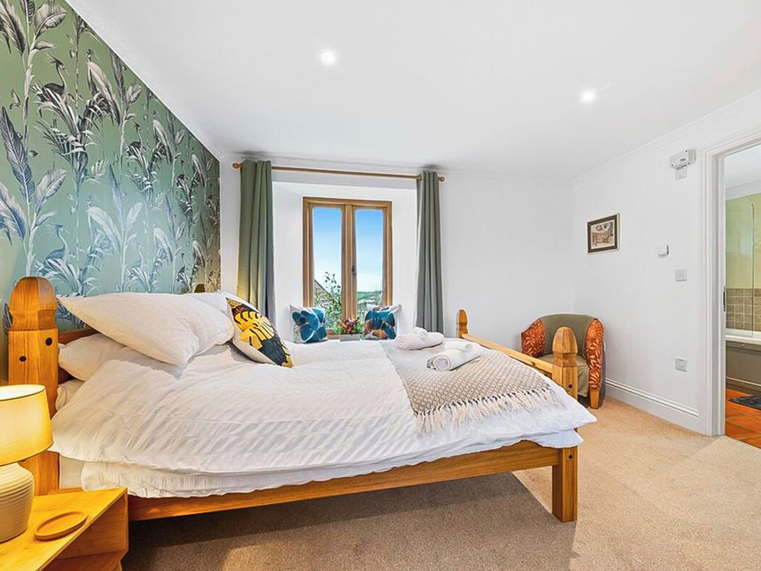 Een slaapkamer met een bed, nachtkastje, stoel, raam en deur.